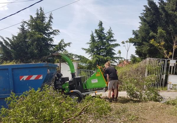 Štiepkovanie konárov pri čistení pozemku, biomasa do kontajnera